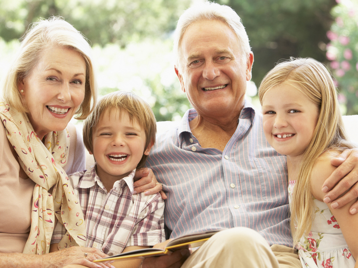 Großeltern mit Enkelkindern lesen ein Buch